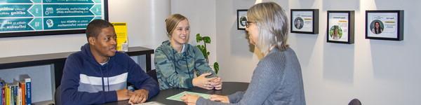 Janelle Andrineini sits across from a female and male student in the Career Center.