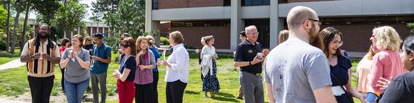 A large group of adults gather outside and eat ice cream treats.